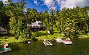 Aerial photo of a house on a lake surrounded by trees with docks and boats in the lake