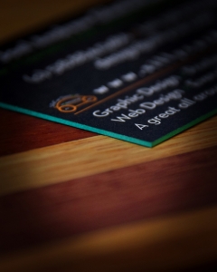 Stylized closeup photo of SillyCar Design business card with green painted edge.