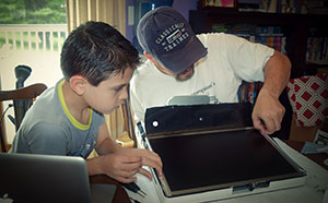 Father and son working together to repair an Apple iMac