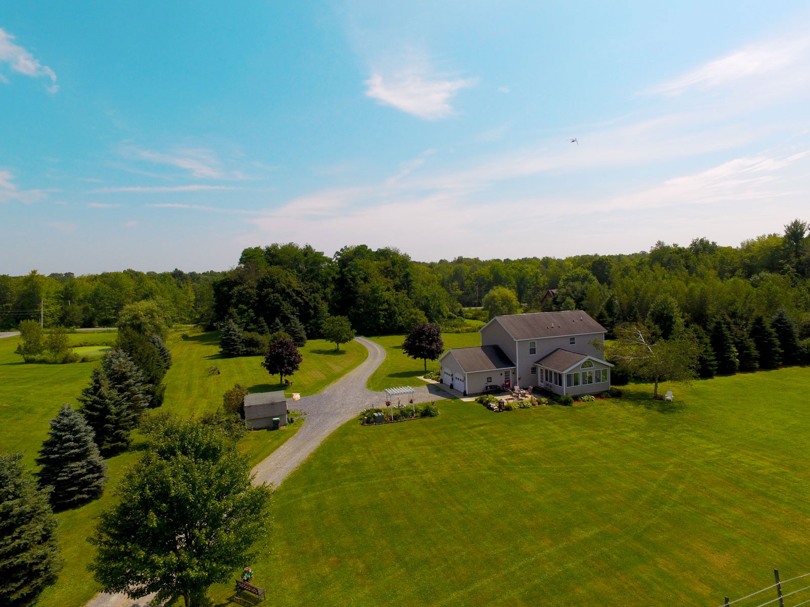 Aerial photo of back of house with helicopter in the sky at property in Amsterdam, New York.