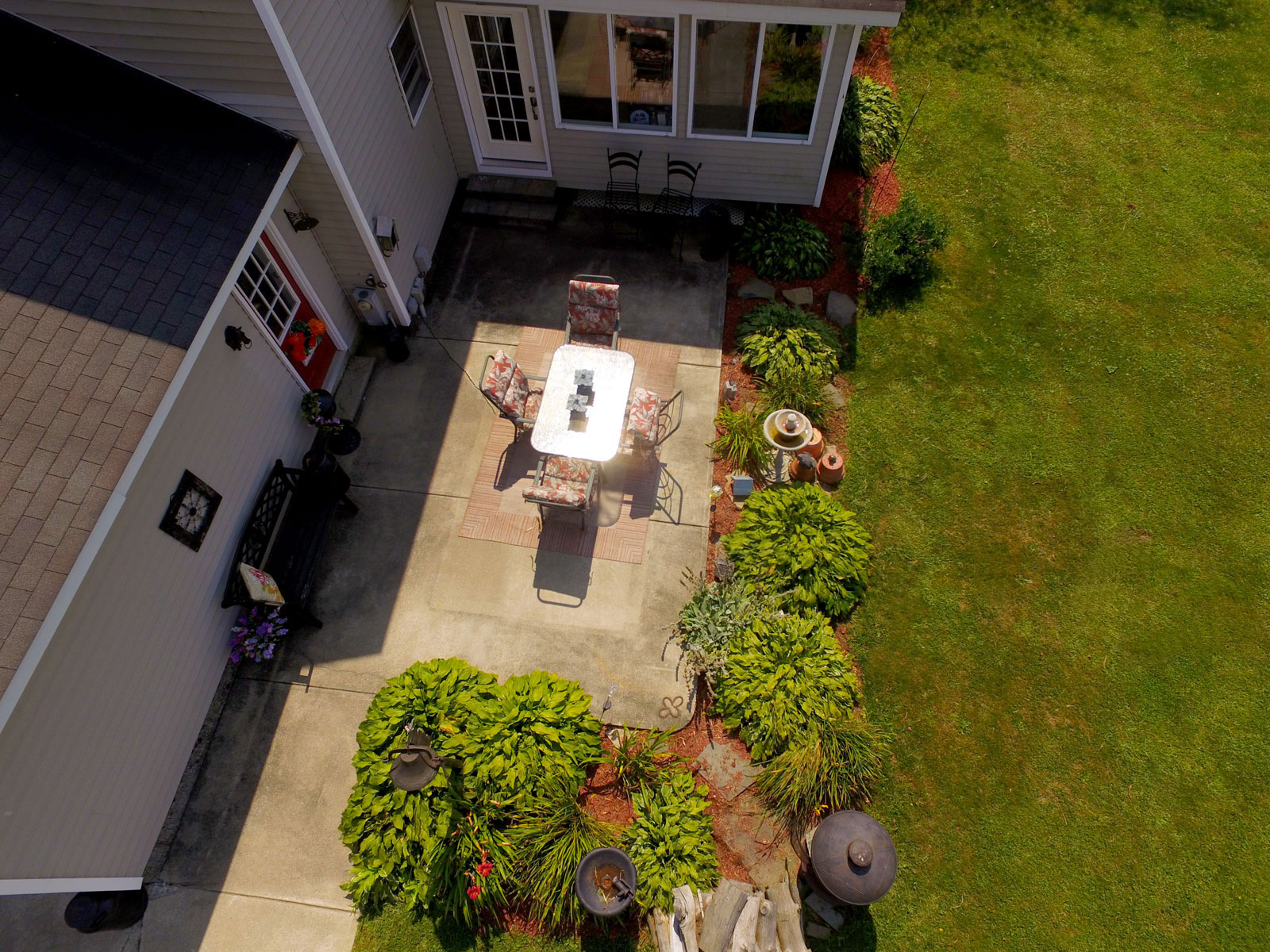 Top down aerial photo of landscaped back patio with table and chairs at property in Amsterdam, New York.