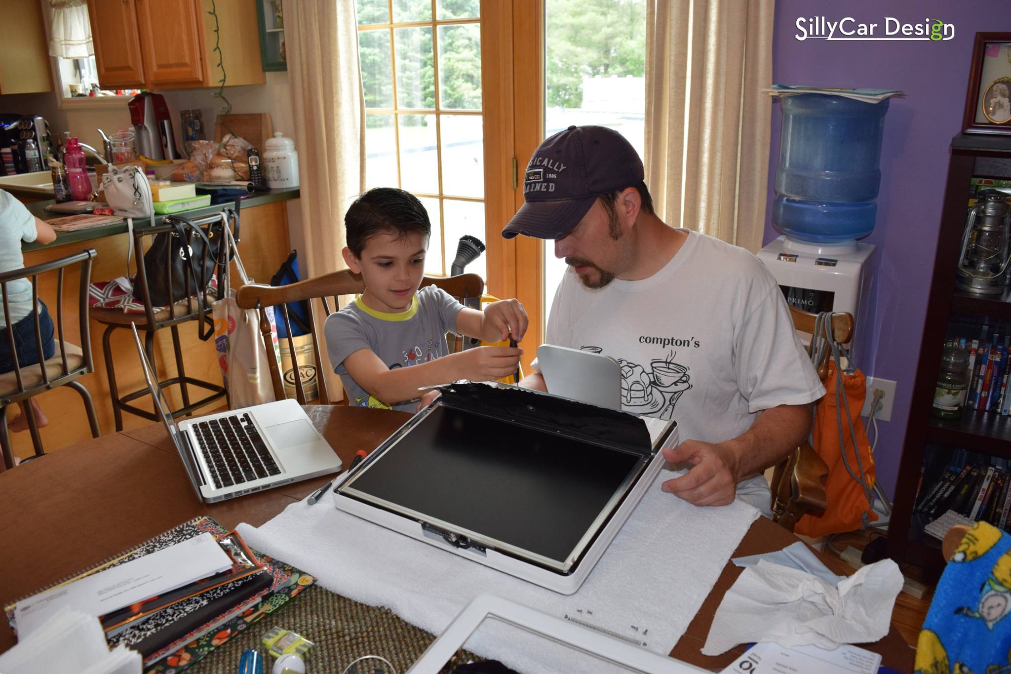 Photo of Joel and Jack Glastetter working together to repair an iMac.