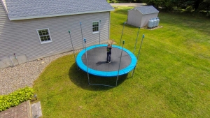 Aerial photo of young boy jumping on trampoline in backyard.